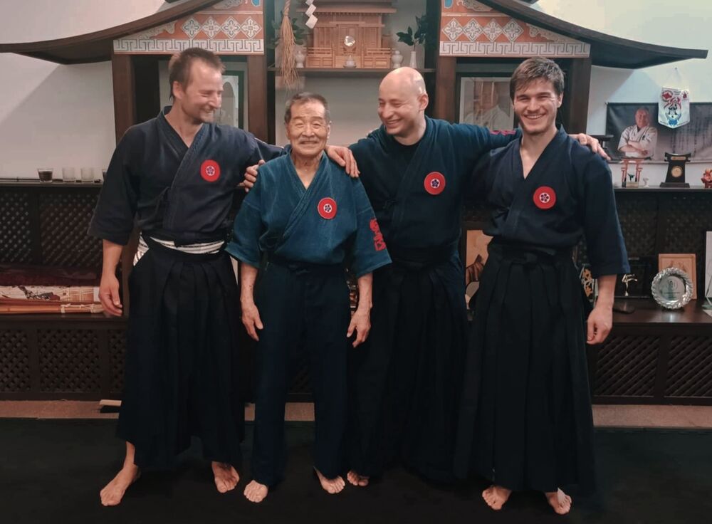 Velmistr Koshiro Tanaka s týmem školy v modrých kimonech a hakama před oltářem dojo